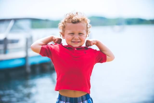 A young Visionary™ boy flexing his muscles in front of a dock.